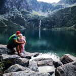 A father and daughter bonding by a peaceful mountain lake with scenic views and clear water.
