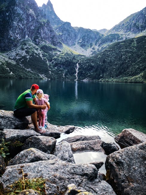 A father and daughter bonding by a peaceful mountain lake with scenic views and clear water.