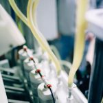 Detailed view of a bottling line in a high-tech brewery focusing on hoses and machinery.