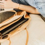 Stylish leather tote bag on couch with a laptop, perfect for work and travel.